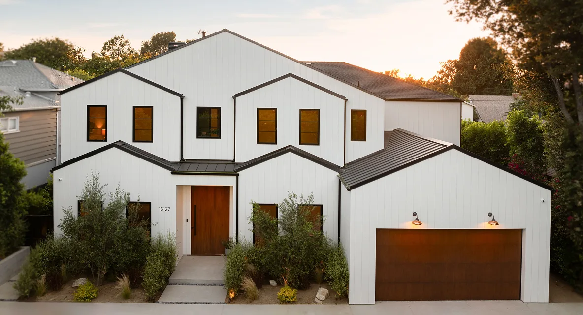 A two-story white house with a dark roof at dusk